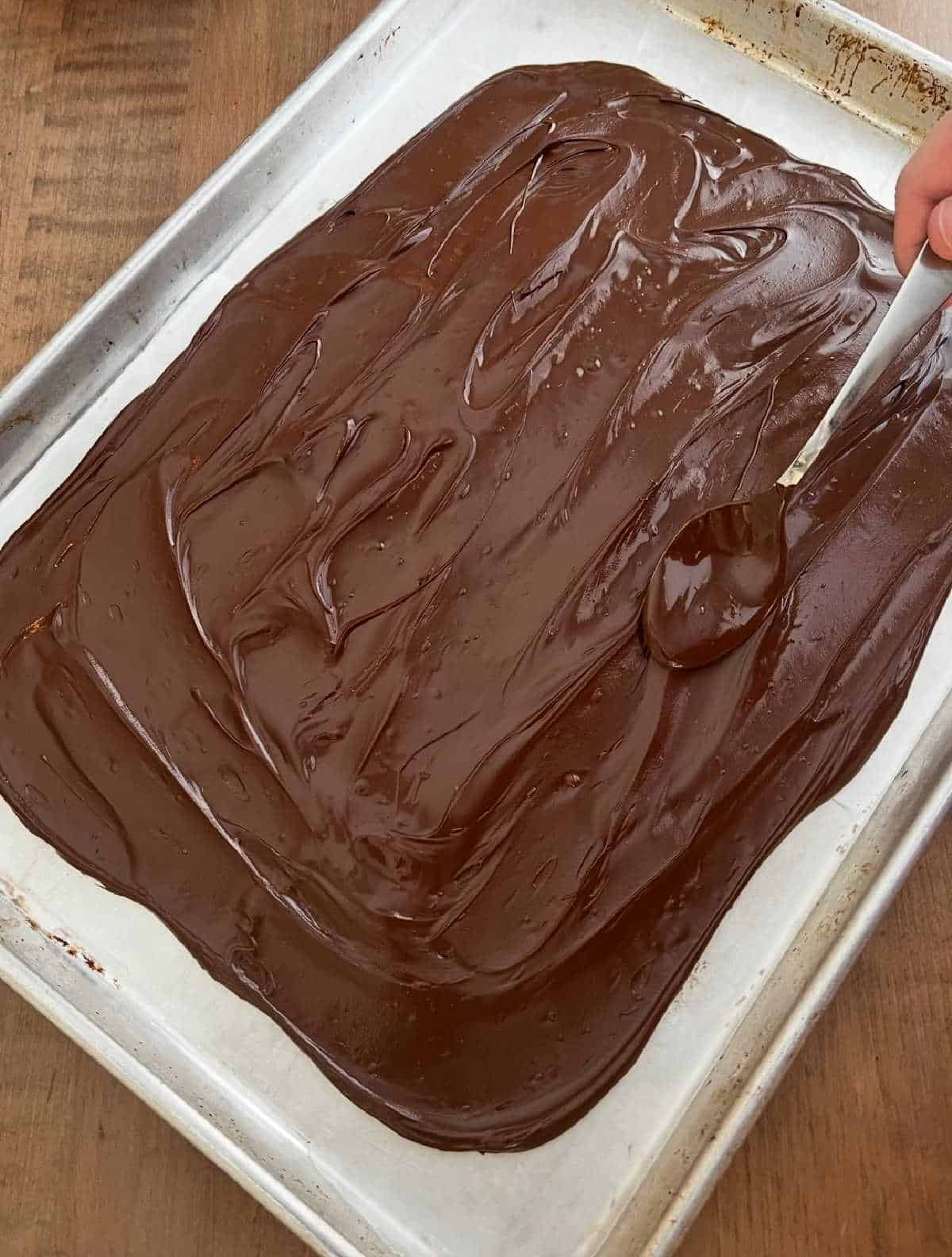 spreading melted chocolate on baking sheet.