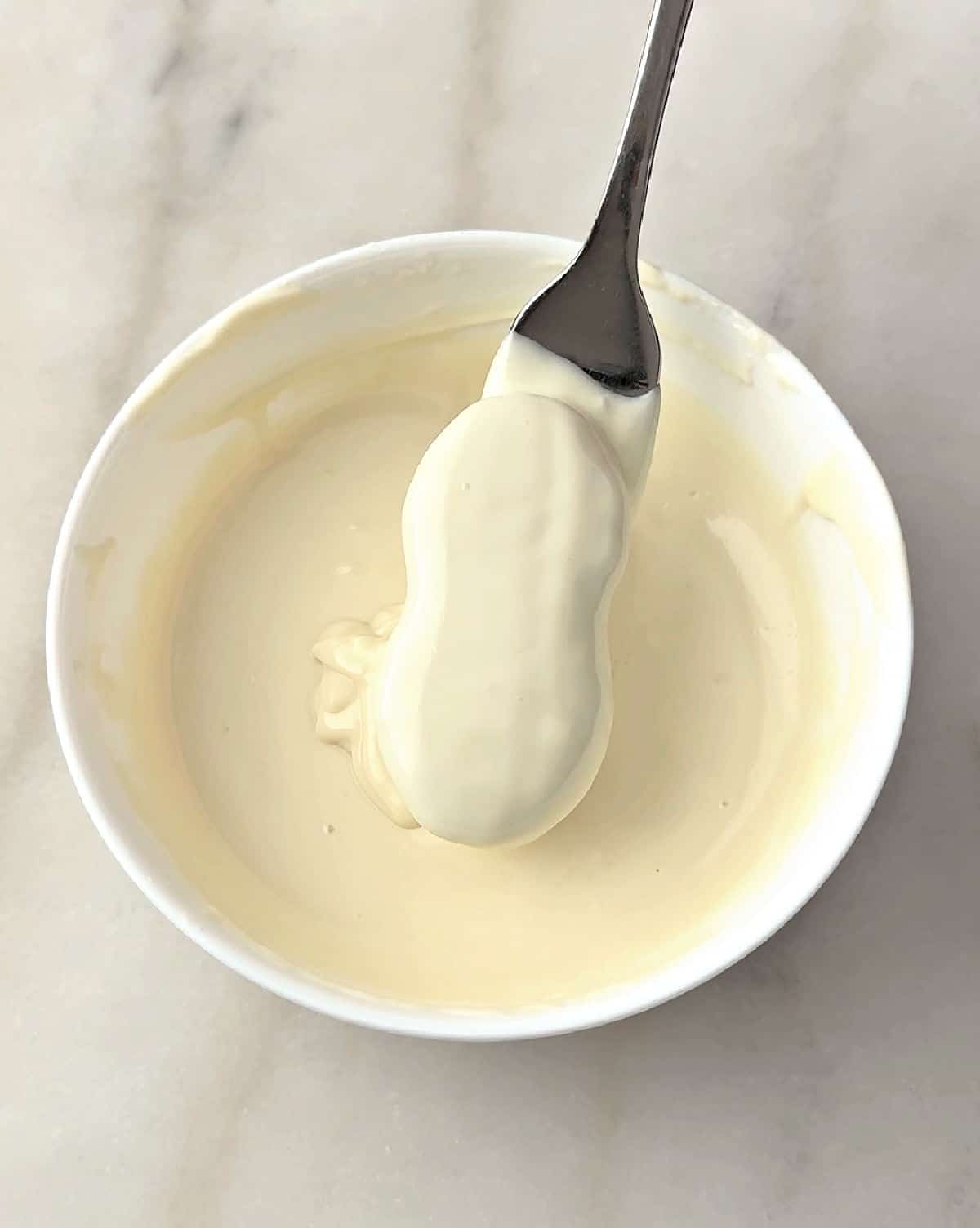 dipping nutter butter into white chocolate on fork.