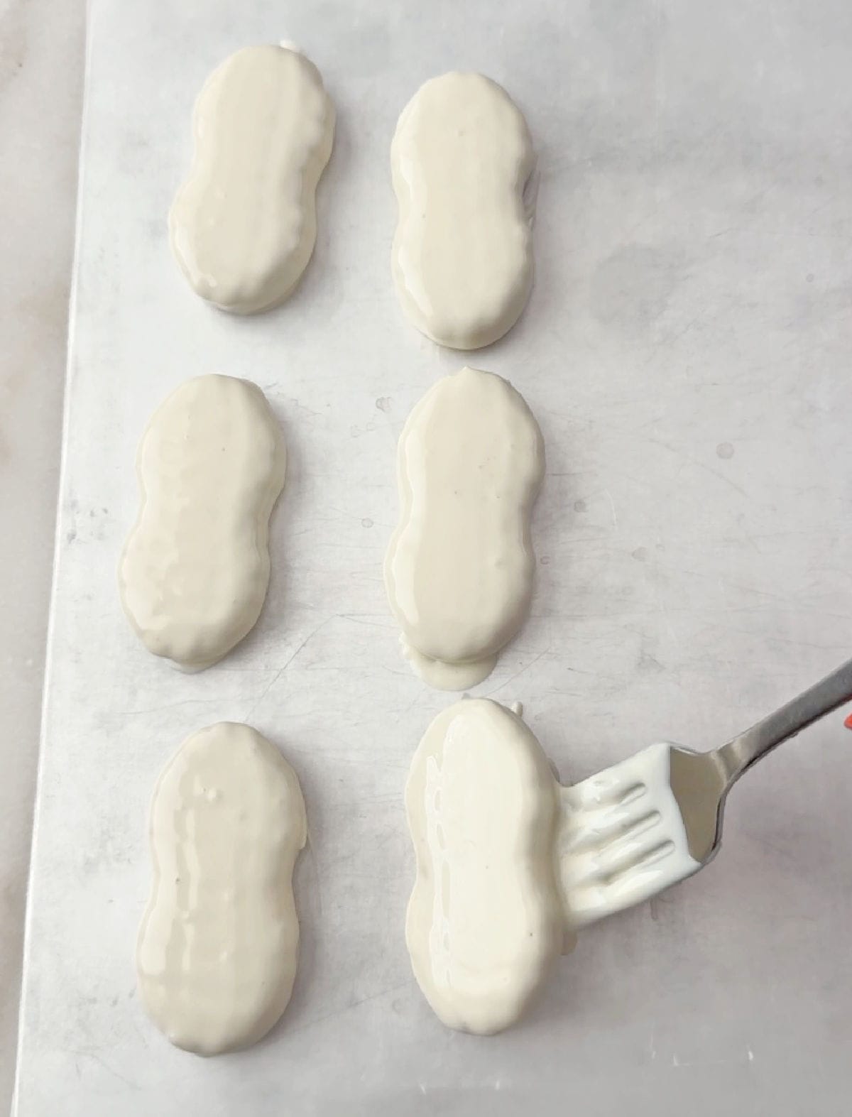 placing dipped ghost cookies on cookie sheet.