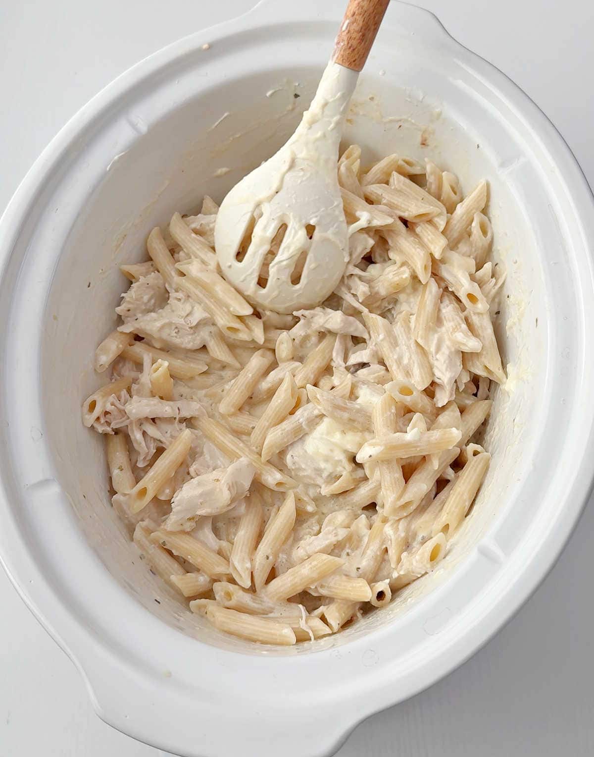 mixing cooked pasta, chicken and sauce with spoon.