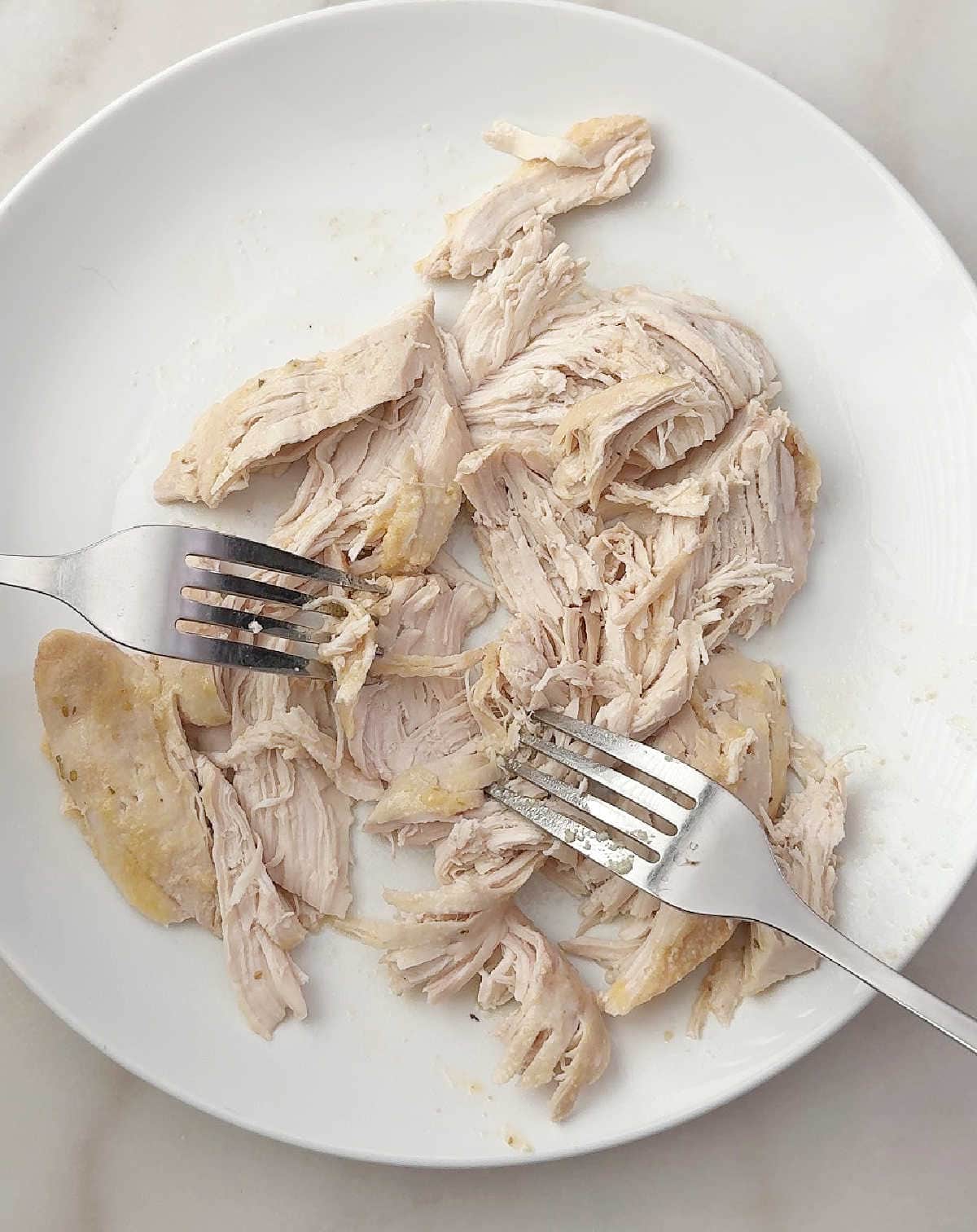 shredding chicken with forks.