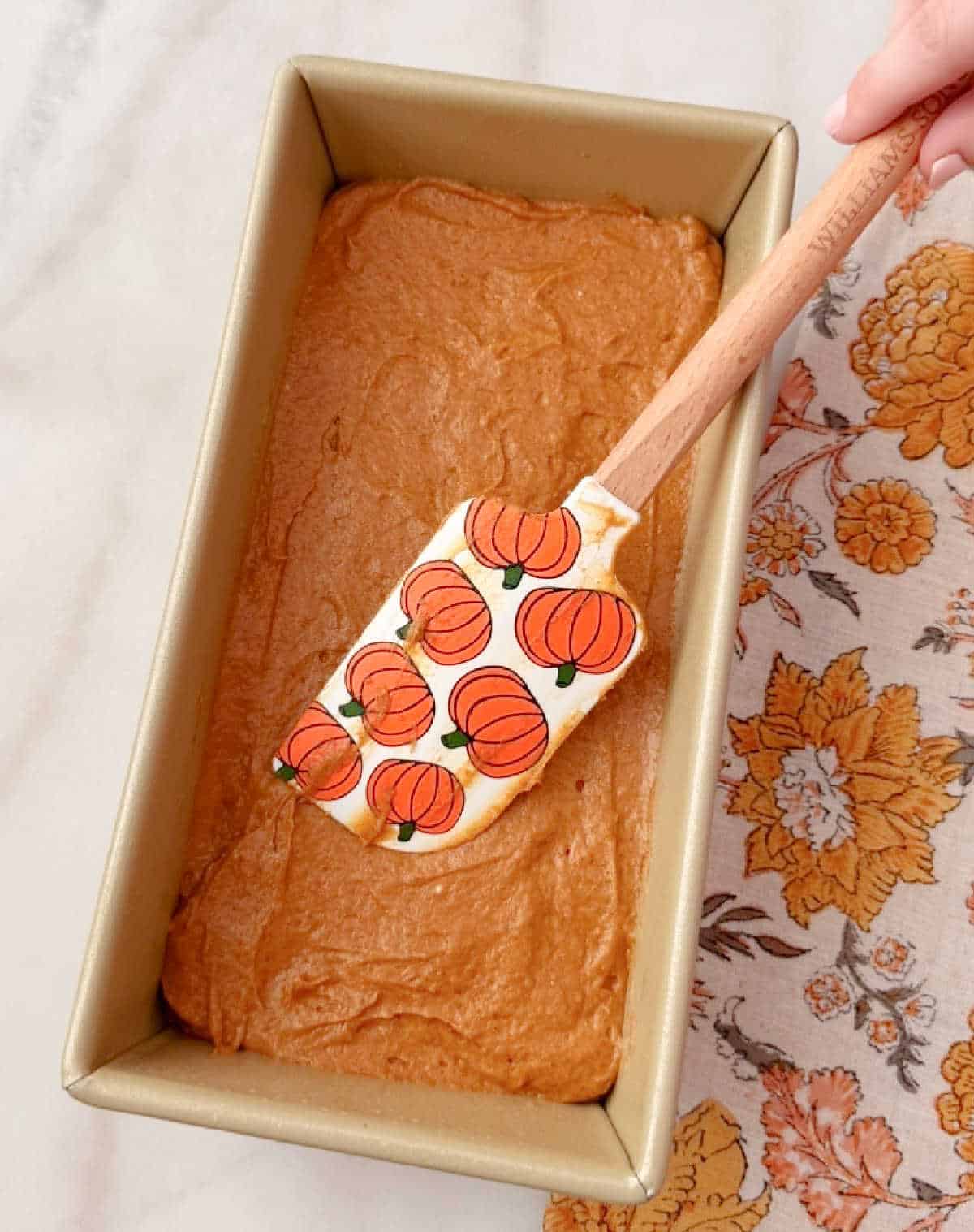 smoothing pumpkin bread batter into loaf pan.