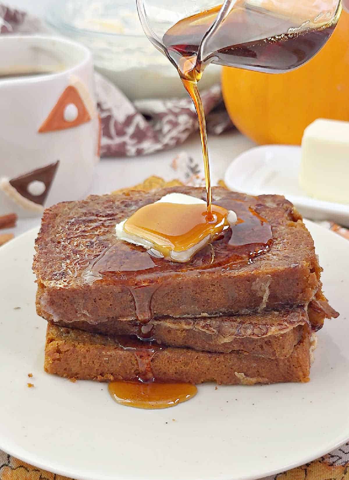 pouring maple syrup on pumpkin bread French toast stack.