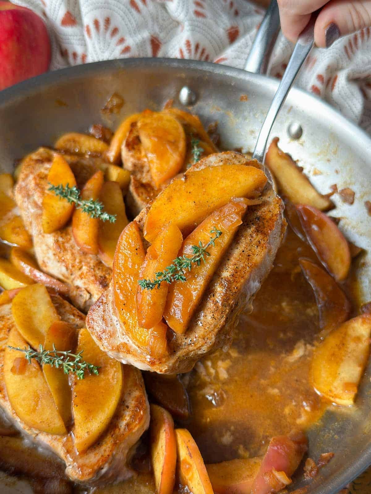 pork chops with apple cider glaze and fried apples on spoon.