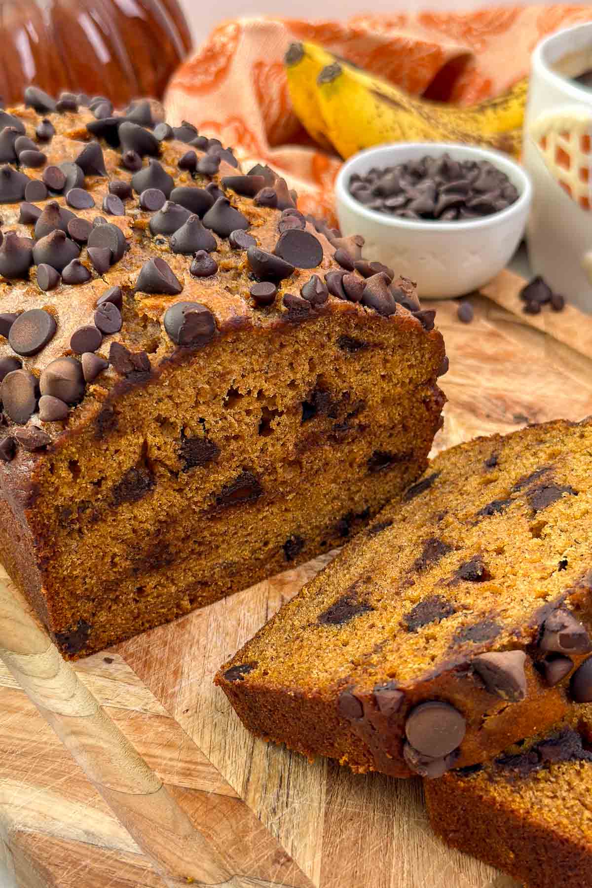 pumpkin banana bread sliced on cutting board with chocolate chips.