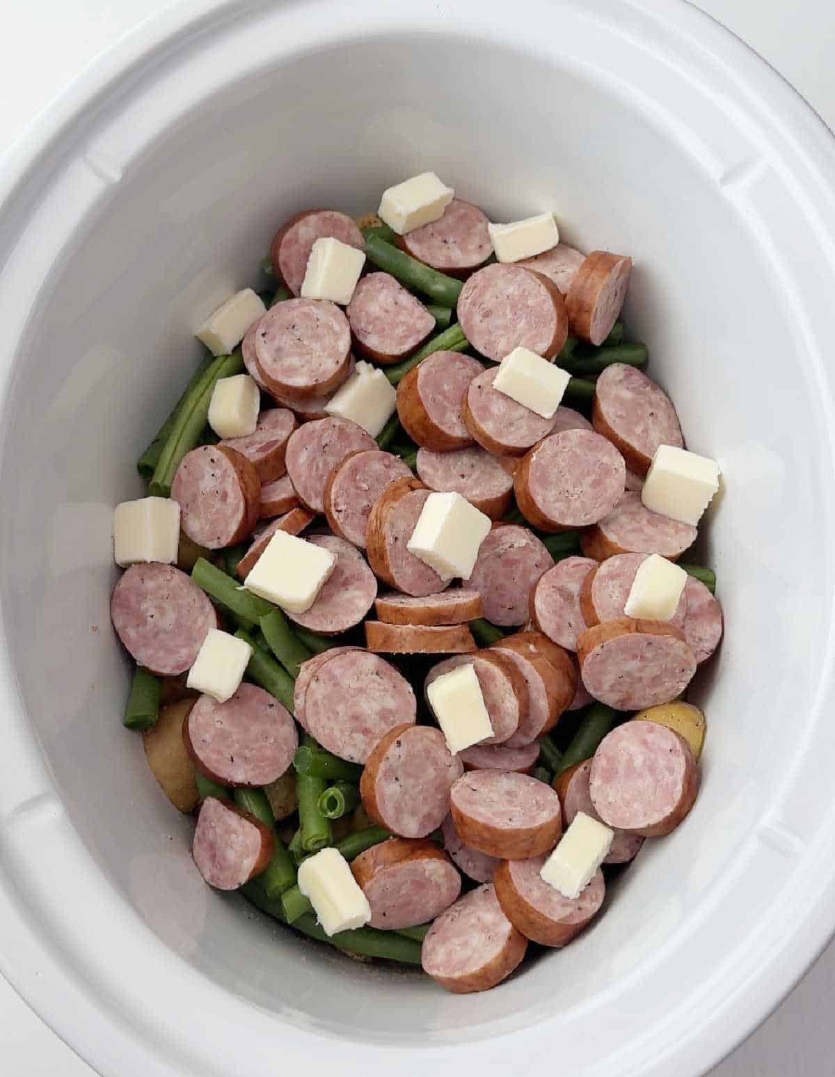 cubes of butter on top of ingredients in crock pot.