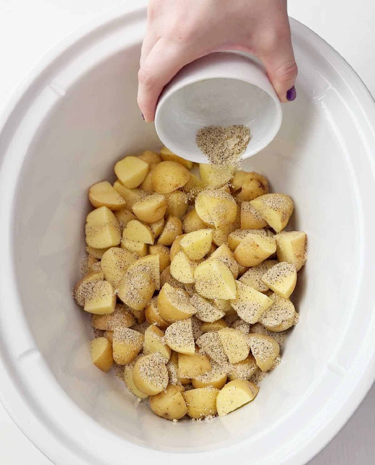 adding seasoning over potatoes.