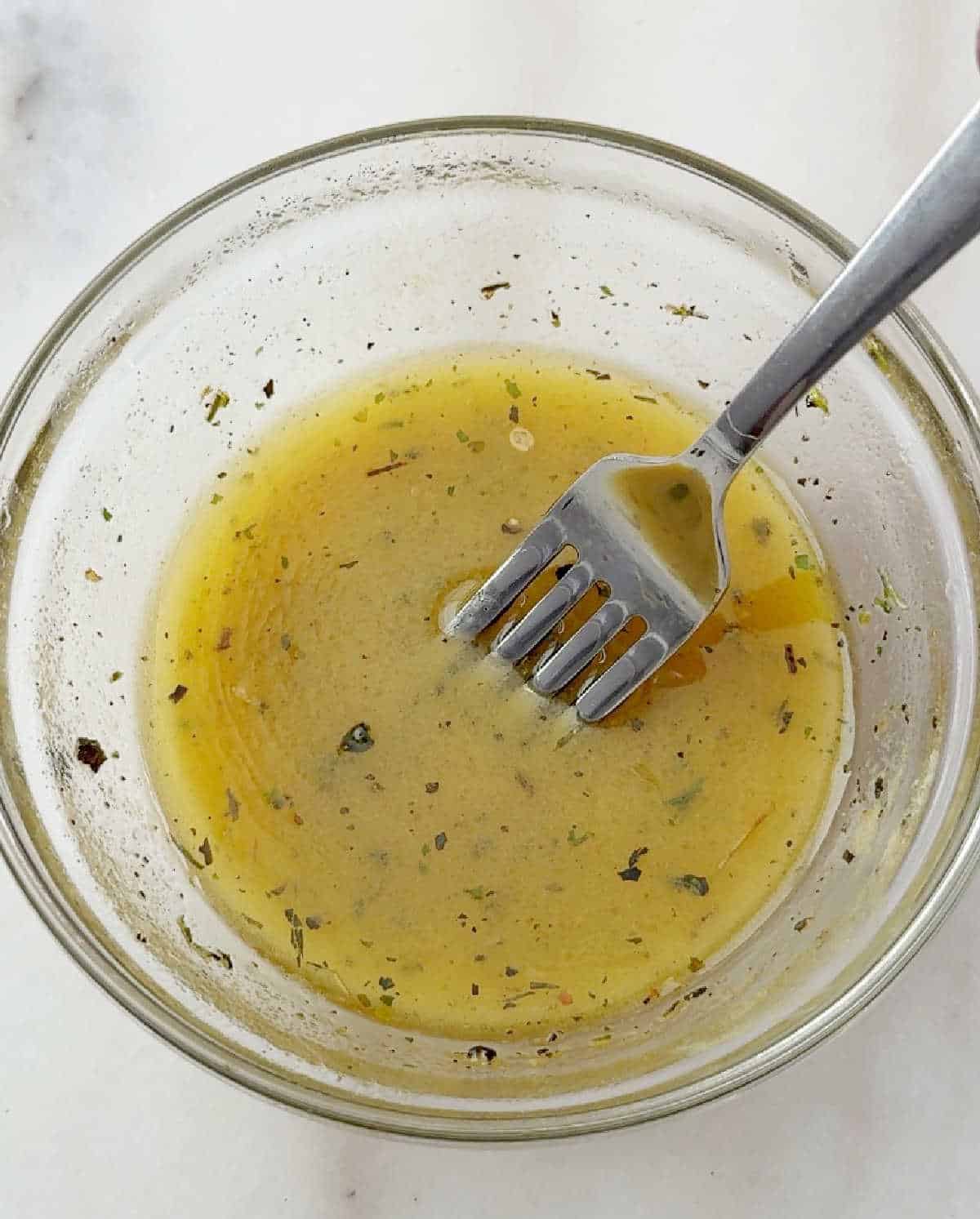 whisking dressing in glass bowl.