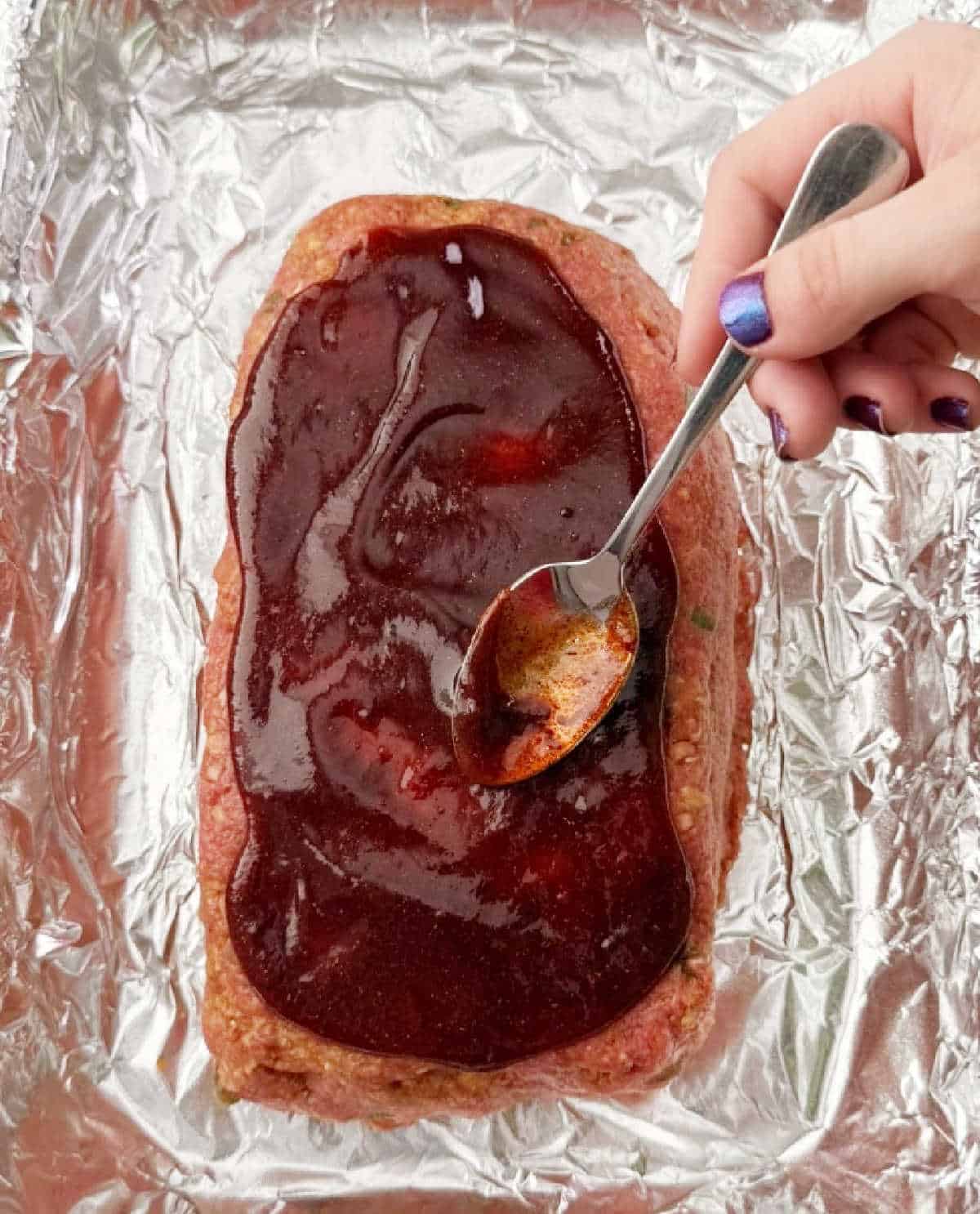 brushing glaze on top of loaf with spoon.