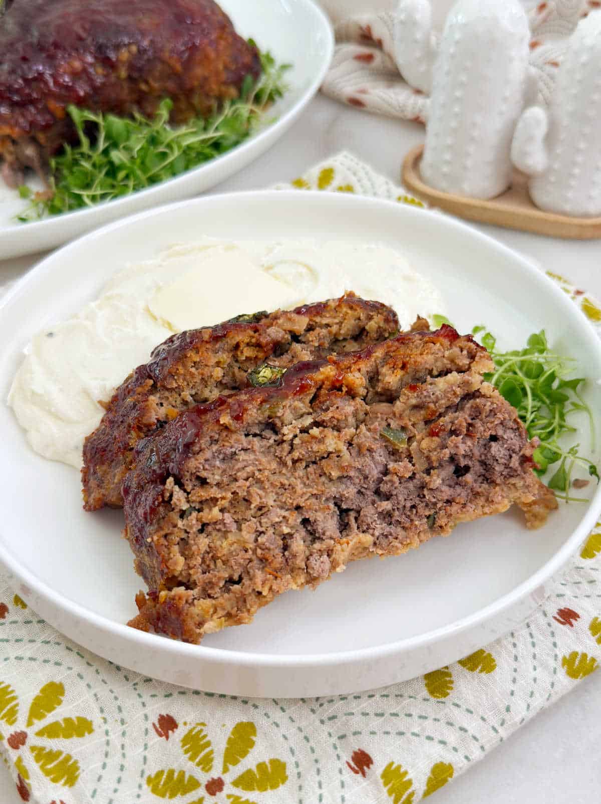 slices of Mexican meatloaf with mashed potatoes on white plate.