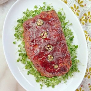 Mexican meatloaf recipe on a platter with arugula sprouts.