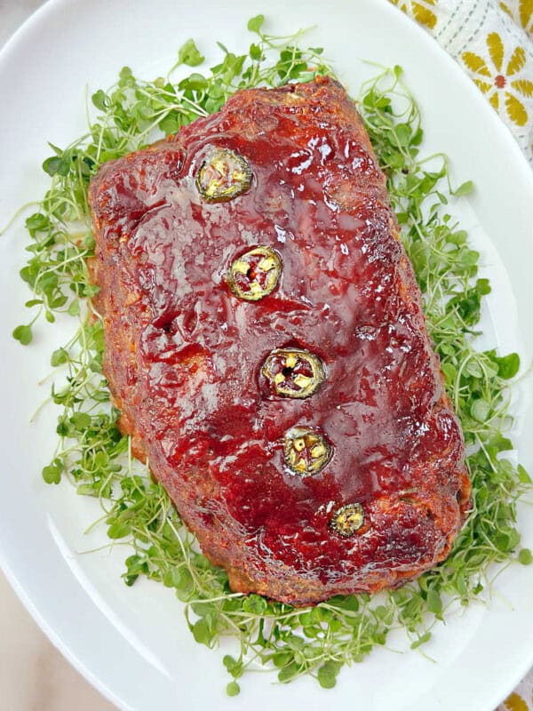 Mexican meatloaf recipe on a platter with arugula sprouts.