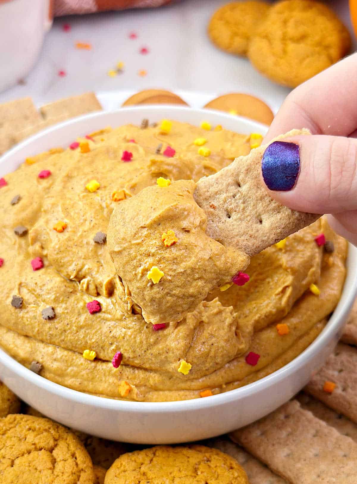 dipping graham cracker into pumpkin pie dip.
