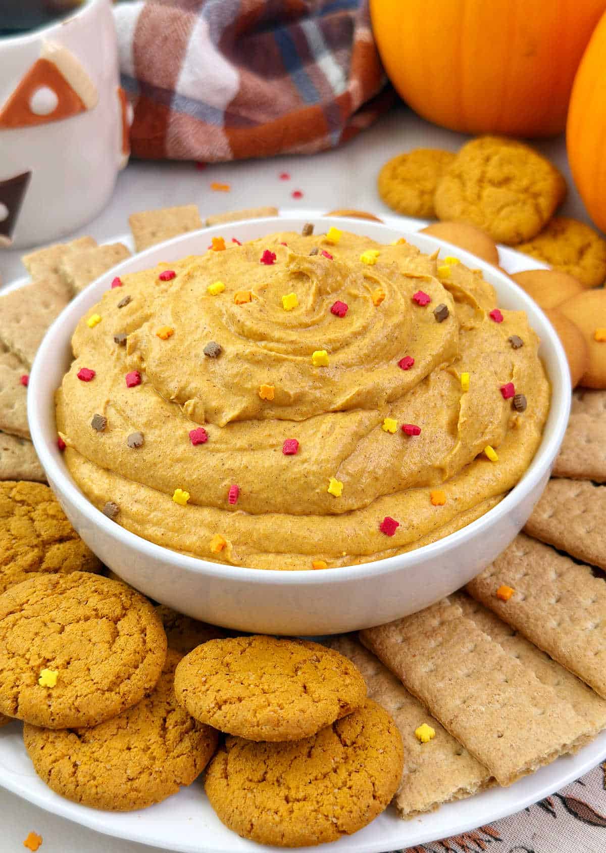 pumpkin pie dip with fall sprinkles and dippers in bowl.