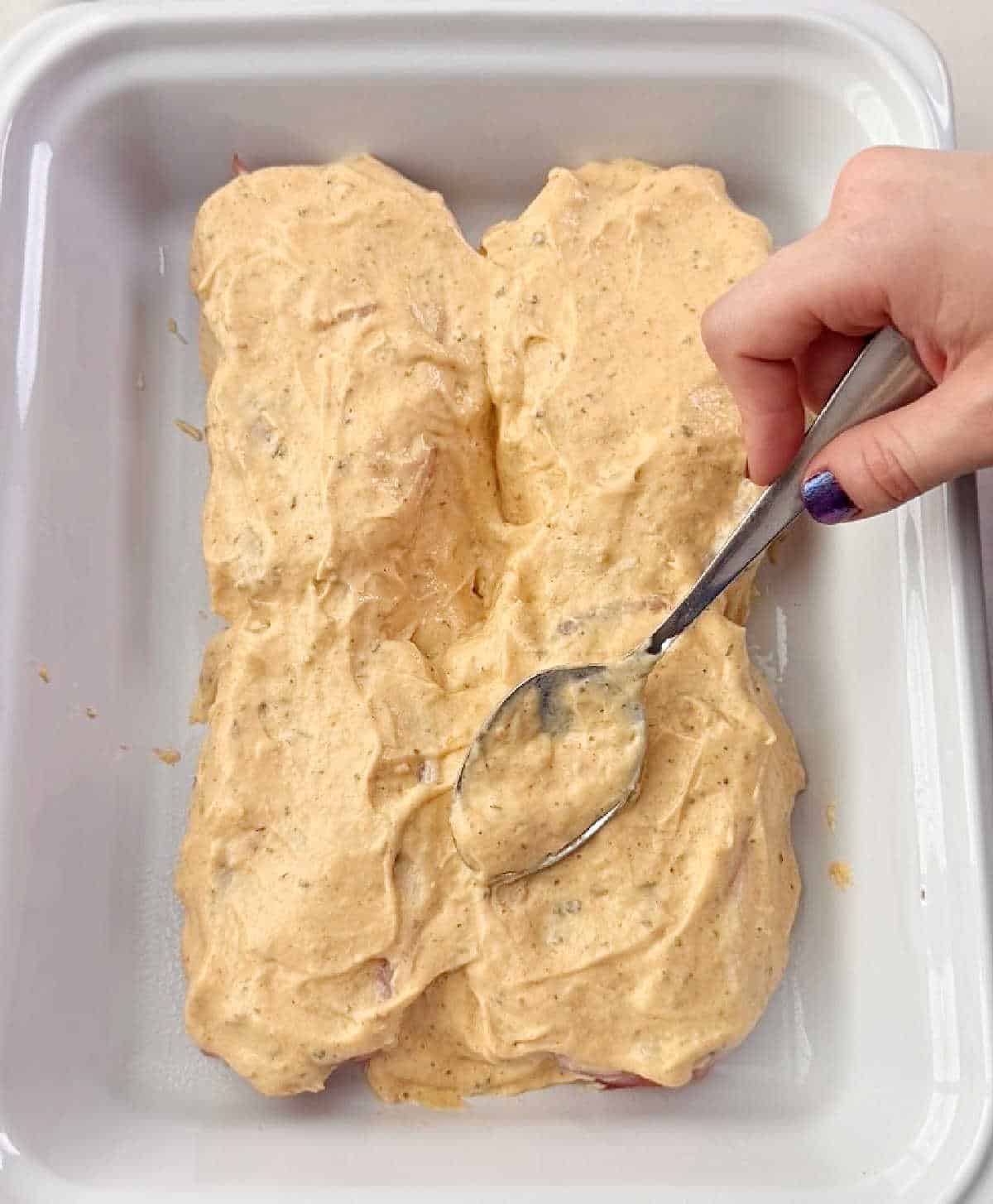 spreading soup mixture over pork chops with spoon.